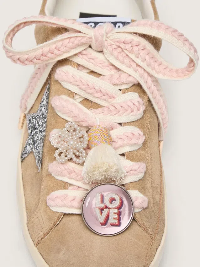 Schnürsenkel aus Lederwaren in Hellbeige mit rosa Zierband, Anstecknadel und Applikationen